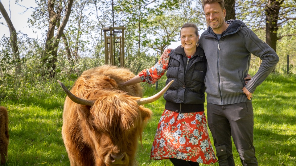 Matthias und Nicolle Schilling, die neben einem braunen Highland Rind stehen.