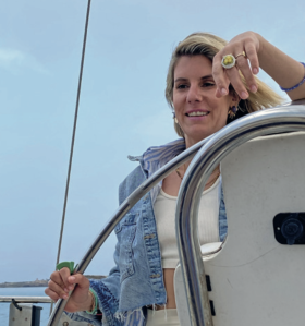 Fernsehköchin Felicitas Then lehnt an einem großen Steuerrad einer Segeljacht.